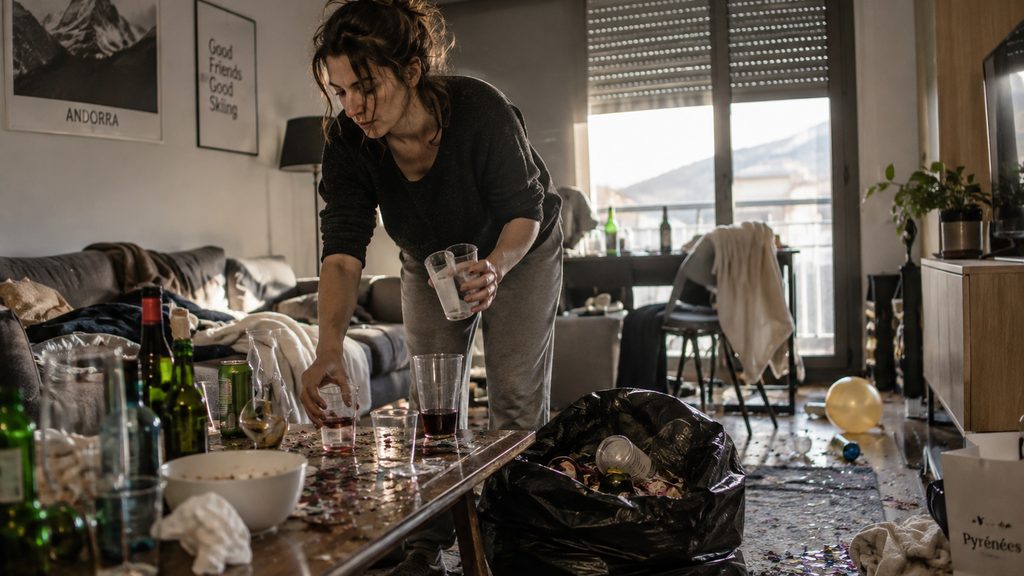 Mujer recogiendo vasos en el salón de un piso de Andorra la mañana después de una fiesta