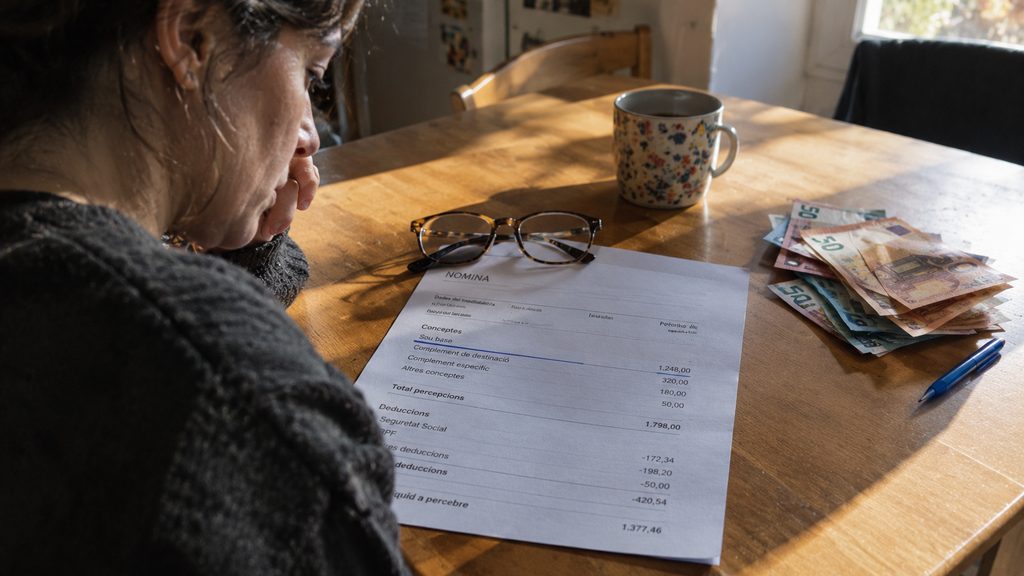 Nómina sobre la mesa con el sueldo base subrayado junto a unos billetes en una casa de Andorra