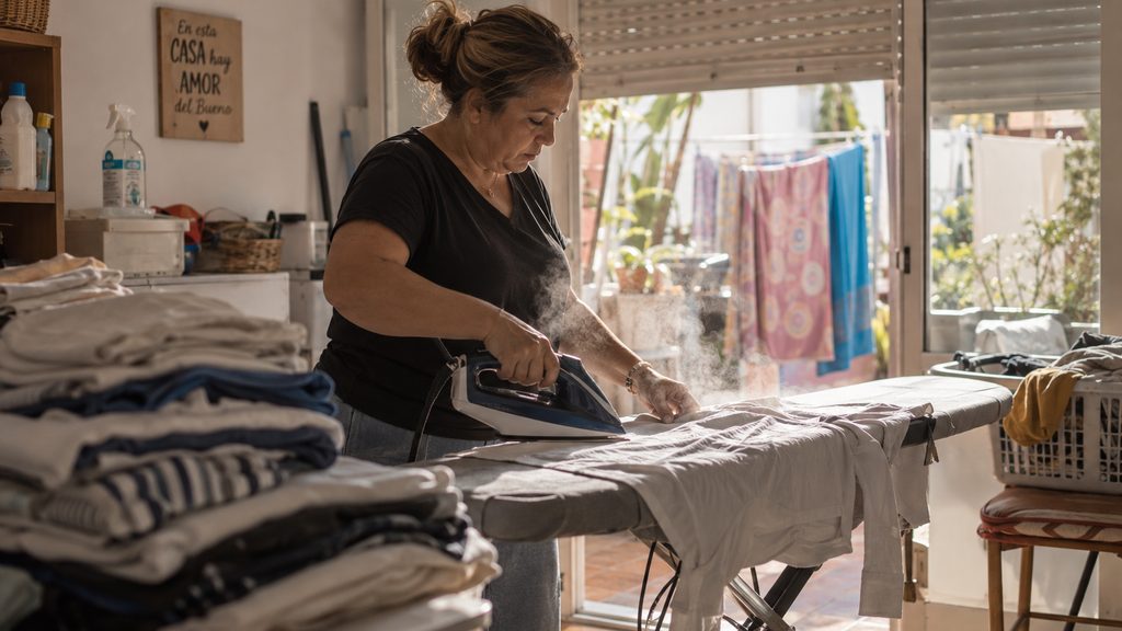 Trabajadora de limpieza en un cuarto de plancha durante su jornada en Motril